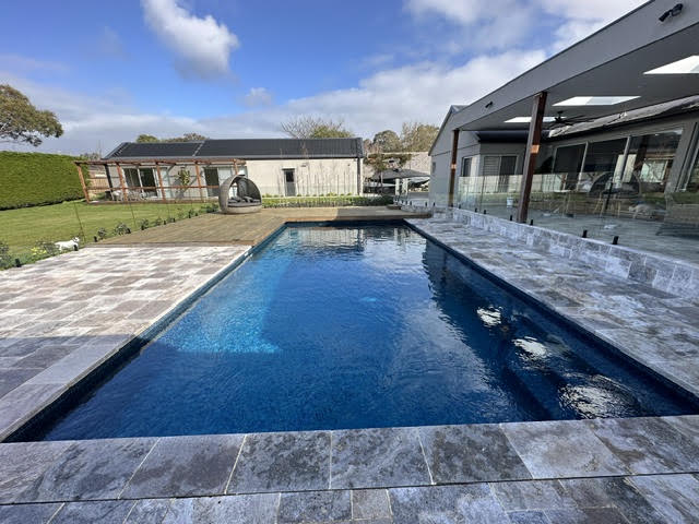 Modern Melbourne backyard pool with stone paving and outdoor living